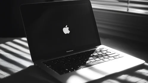 Closed laptop on bed with strong window light pattern.