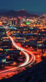 Elevated view of illuminated city and curved traffic trail.