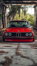 Classic red BMW coupe sits low in abandoned industrial hall.