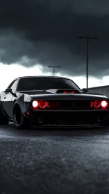 Low-angle view of black muscle car under dark storm clouds.