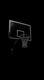 Basketball hoop emerges from deep black night sky backdrop.