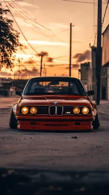 Low-slung red BMW classic under warm urban sunset light.