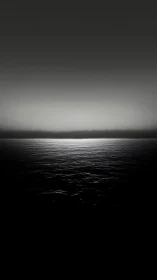 Midnight horizon where silver water meets quiet void.
