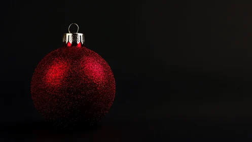 Red spherical ornament is positioned against a black background