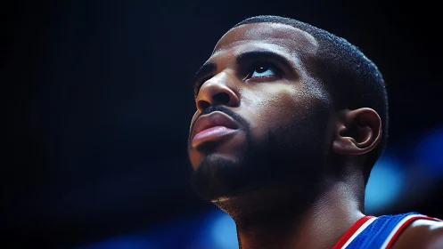 Focused basketball player under arena lights in profile.