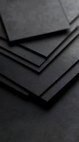 Stacked matte black sheets form layered geometric surface planes