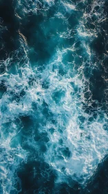 Turbulent teal ocean waves crash and churn in overhead view