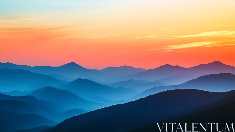 Sunset gradients over layered blue mountain ridges.