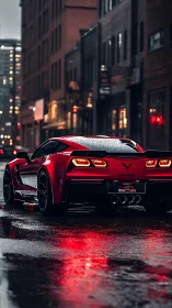 Red sports coupe glows on wet downtown street at dusk.