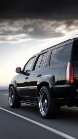 Black luxury SUV cruises along highway under storm clouds