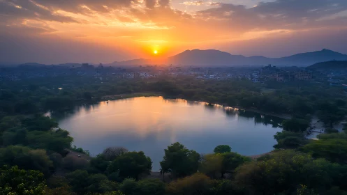Sunset over urban lake with distant hills and skyline.