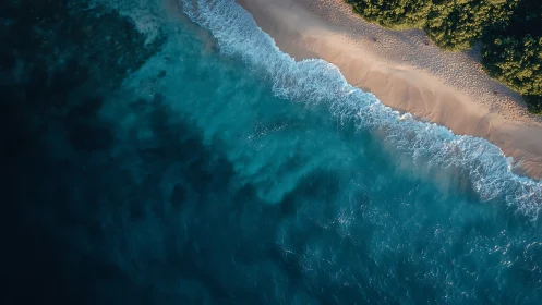 Aerial view of blue ocean waves meeting sandy shore.