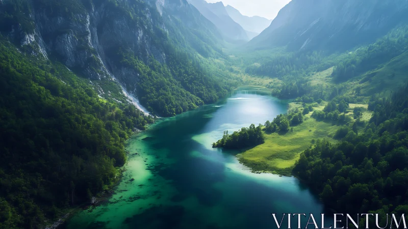 Emerald alpine lake winding through misty mountain valley.