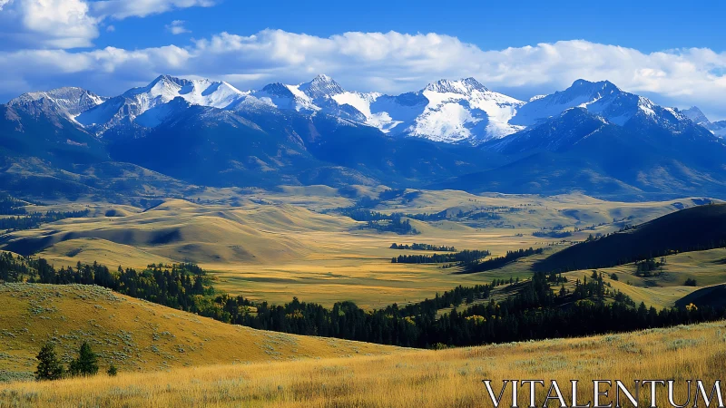 Snowcapped mountain range above sunlit rolling valley panorama.