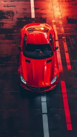 Red sports car on wet road under warm urban lights.