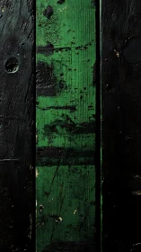 Vertical green plank divides rough black painted surface