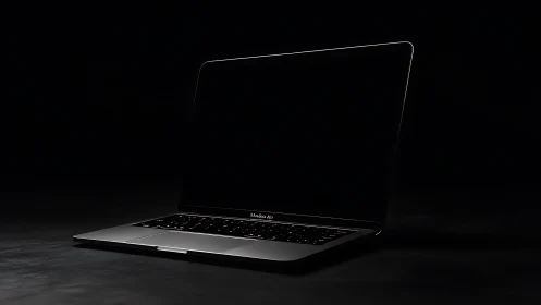Sleek laptop computer in dark studio with minimalist lighting.