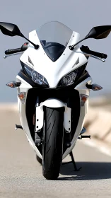 White sport motorcycle is positioned front-on on open road