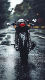 Lone cafe racer idling bold on rain-slicked city asphalt.