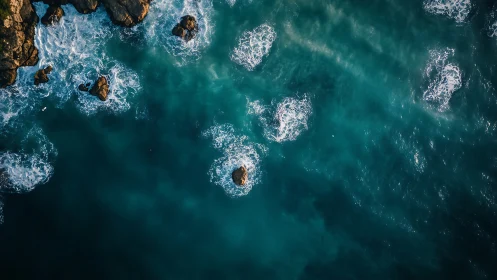 Foamy circles chase quiet rocks through teal ocean glass