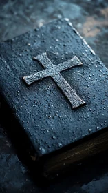 Rain-dimmed prayer book crowned by a weathered metal cross.
