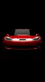 Red sports coupe front view under dramatic black lighting.