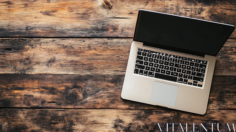 Cozy laptop workspace on a rustic wooden desktop surface.