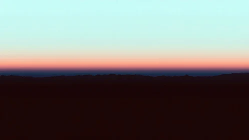 Desert ridgeline rests beneath layered pastel twilight sky.