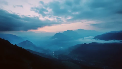 Blue hour aerial mountain valley under stratified cloud deck