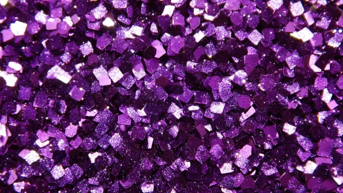 Purple glitter macro texture with faceted reflective hexagons.
