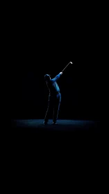 Golfer silhouette swings under dramatic low key spotlight.