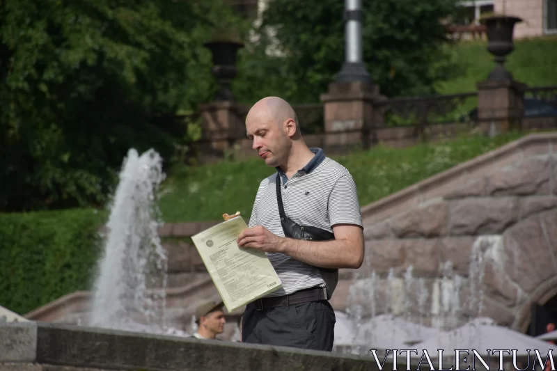 Ukrainian Man Reading by City Fountain Free Stock Photo