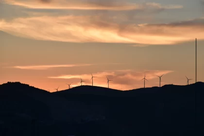 Sunset Wind Turbines on Hilltop with Mountainous Backdrop