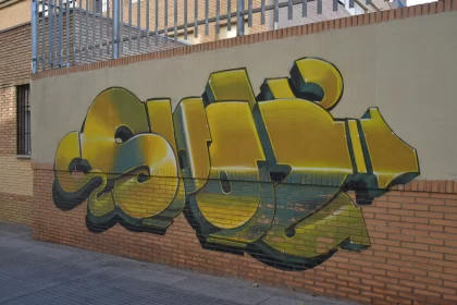 Bronze and Yellow Graffiti on Brick Building Free Stock Photo