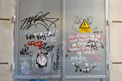 Graffiti-Adorned Silver Door: An Honest Depiction of Urban Life Free Stock Photo