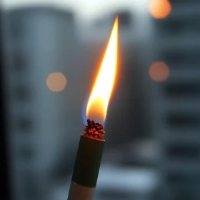 Cigarette with Flame in Front of Blurred Cityscape