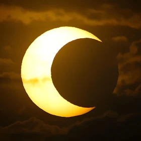 Eclipsed Sun Peeks Through the Clouds