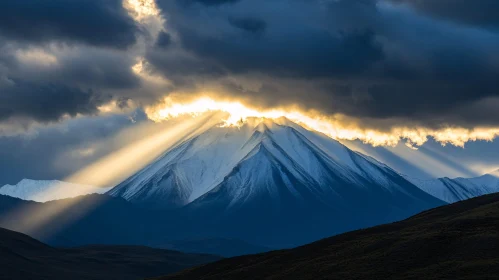 Sunlit Snowy Mountain Under Dramatic Clouds