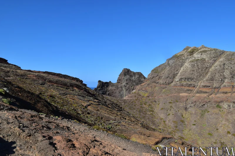 Rugged Mountain Terrain Under Blue Sky Free Stock Photo