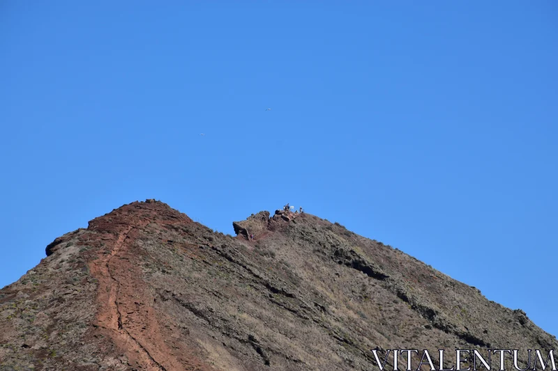 Hikers on Rugged Mountain Summit Free Stock Photo