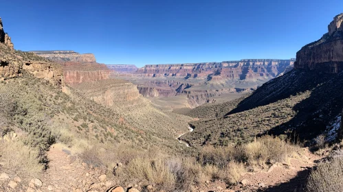 Expansive Canyon View with Cliffs and Arid Terrain under Clear Skies