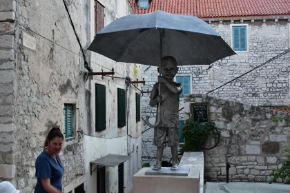 Child Holding Umbrella Statue in Alley