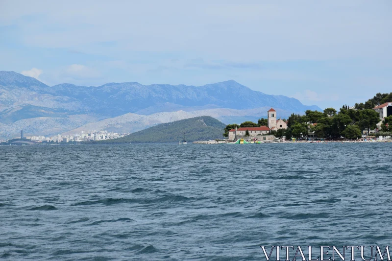 Tranquil Coastal View with Church and Mountains Free Stock Photo