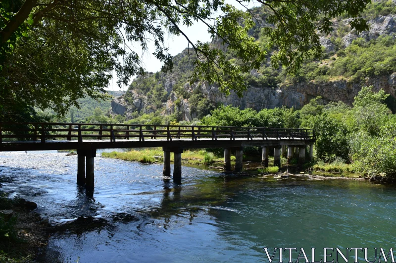 Peaceful Riverside View with Wooden Bridge Free Stock Photo