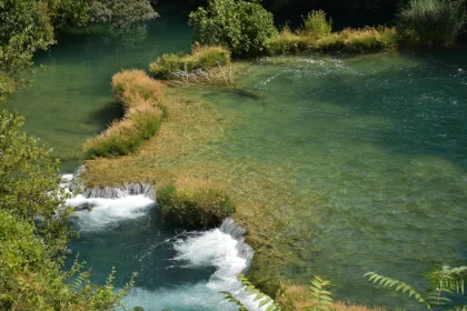 Calm River with Waterfall and Green Surroundings