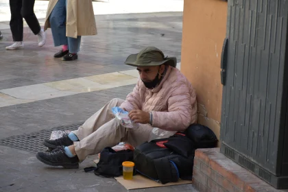 Man Sitting on City Sidewalk