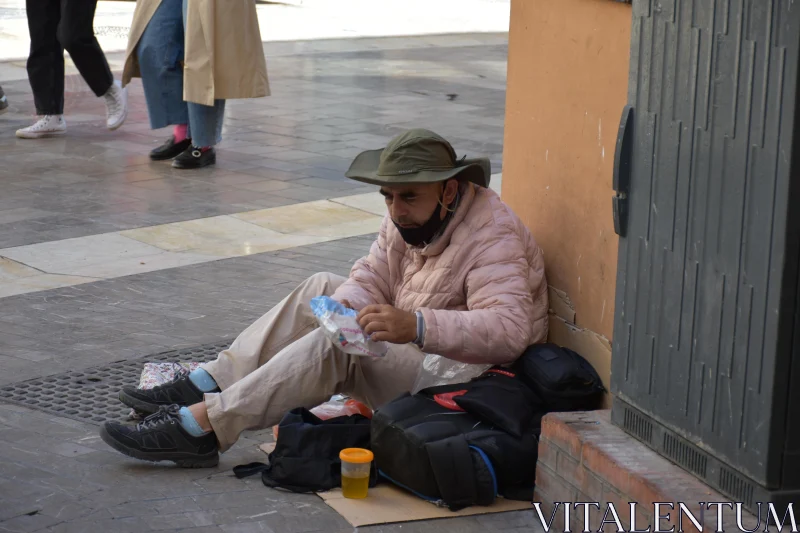 Man Sitting on City Sidewalk Free Stock Photo